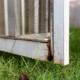 Close-up of rotten wood on exterior screen door of a porch